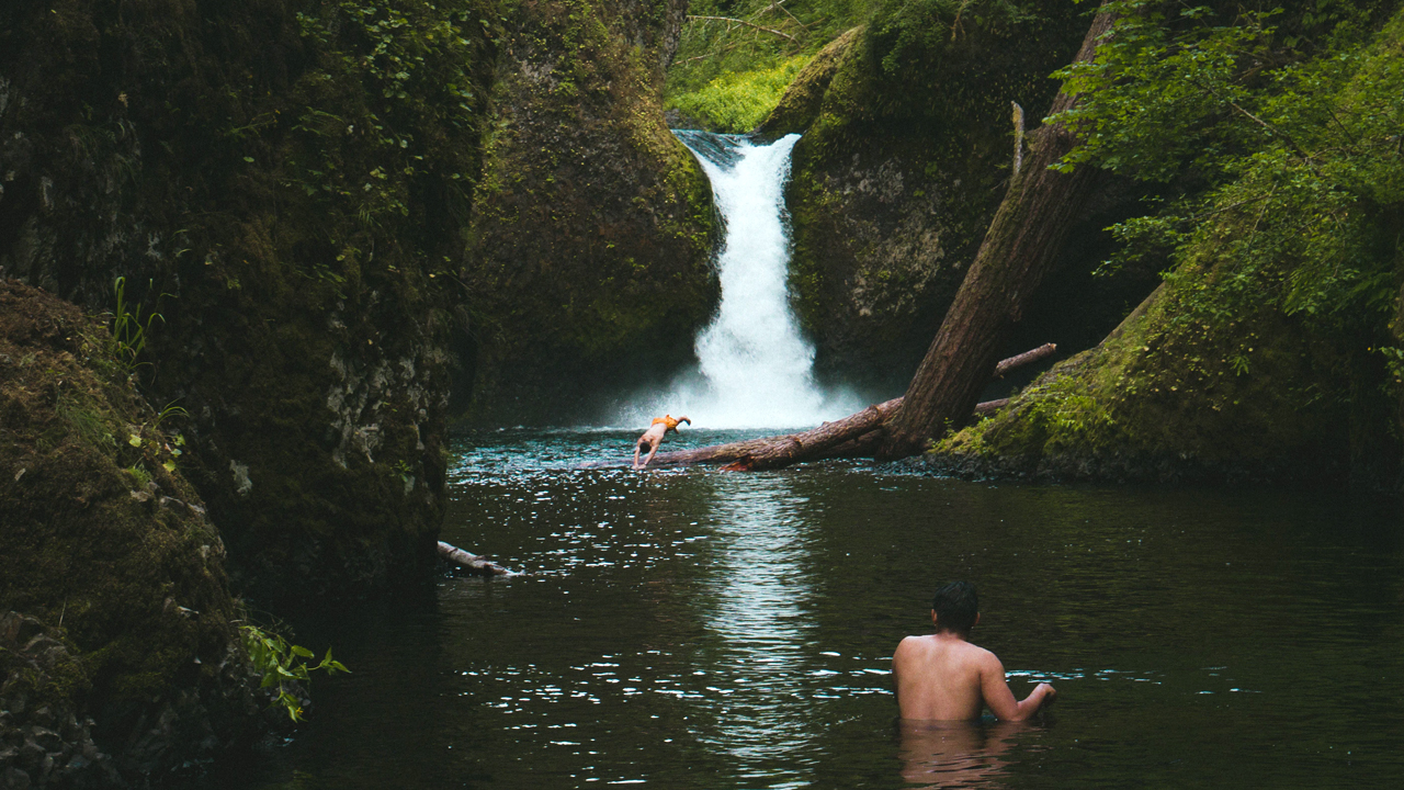 Опасное купание. Купаться в реке. Человек под водопадом. Поплавал в озере с водопадом. Человек купается в водопаде.